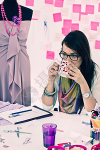 年轻时装设计师在工作室喝咖啡色调形象图片