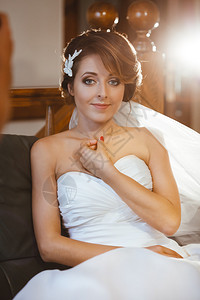 婚前准备坐在沙发上微笑的未婚妻穿着白色婚纱背景图片