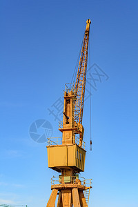 在港口的老黄色起重机有蓝天在背景中图片