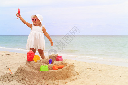 可爱的小女孩玩沙在海滩图片