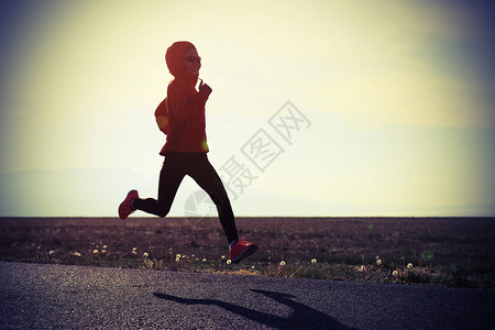 在日出海边的公路上奔跑的年轻健身图片