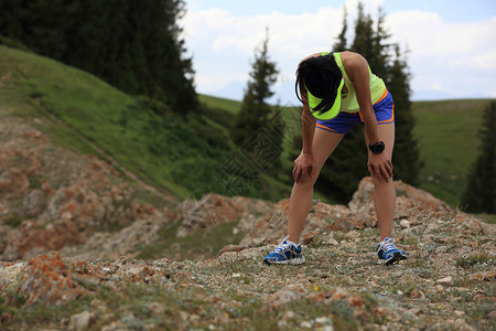 在森林步道上奋力奔跑后休息的疲惫女跑者图片