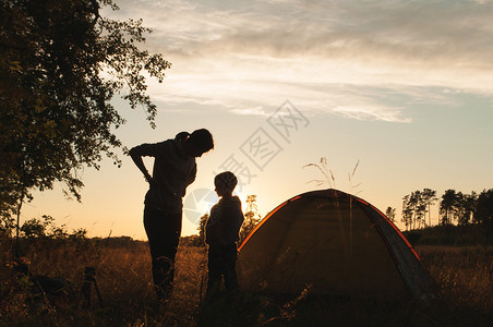 日落时母亲与她儿子在帐篷附近露营图片