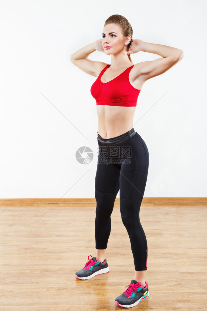 适合穿着士力架黑色紧身裤和红色短上衣的运动型女孩站在健身房手牵头图片