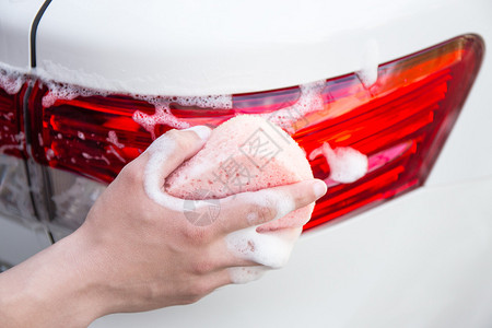 用海绵和肥皂清洗汽车尾灯的男手图片