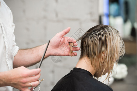 理发师用剪刀头发在专业美发店的英俊满意图片