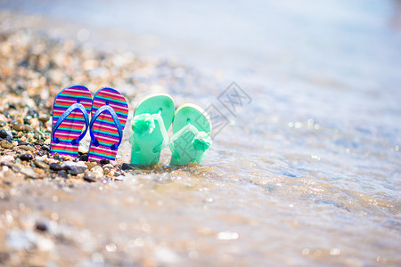 孩子们在蓝色大海前的沙滩上穿拖鞋图片