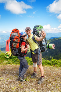 几个徒步旅行者以山景为背景自拍几个游客女人和男人在山上自拍图片