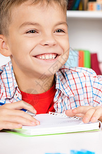 年轻的男孩坐在教室的书桌边在图片