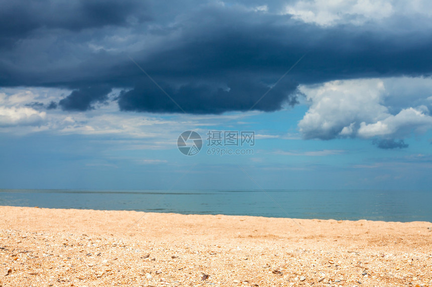 前景焦点与沙滩和深蓝色雨云在海上的景观图片
