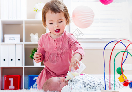 快乐的幼儿女孩喂她新生的图片