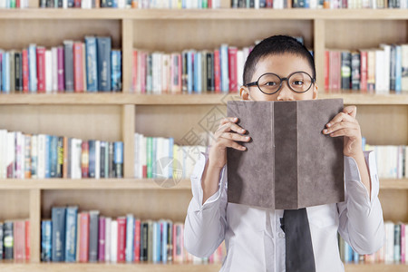 一名小学生用一本书遮盖脸部图片