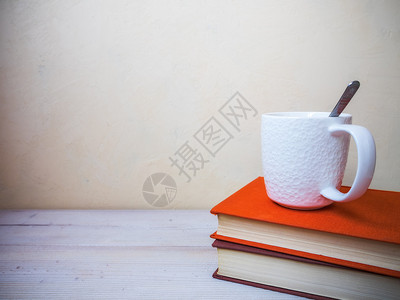 在木制桌上的书本和茶杯上可以看到图片