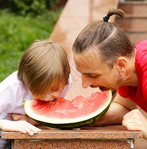 野餐时吃西瓜的父子图片