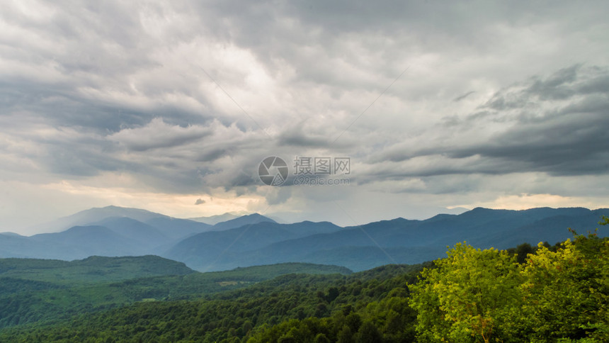 明亮的灰色天空日落时有雷鸣山峰和山图片