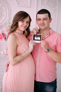 等待婴儿出生的家庭一位孕妇和她的丈夫拿着一个穿着粉色衣服的婴儿图片