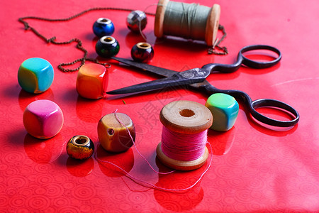 亮红色背景中用于针线活和剪刀的珠子图片