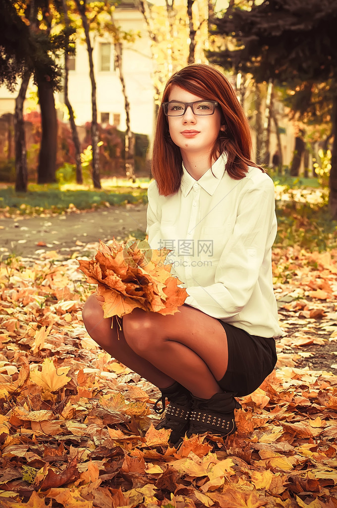 秋天公园里的少女手里拿着枫叶图片
