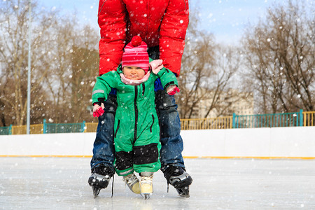 父亲和小女儿在冬天的雪中学习滑冰图片
