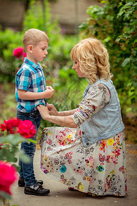 美丽的孕妇带着年幼的儿子在绿色花园里图片