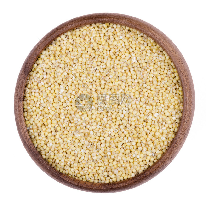 在一个木碗的黄色小米在白色背景小种子被种植为谷类作物或作为饲料和人类食物的谷物可食用生的和有机食品孤立图片