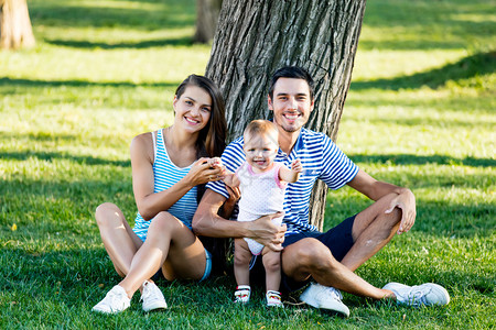 公园树旁幸福家庭的画像图片