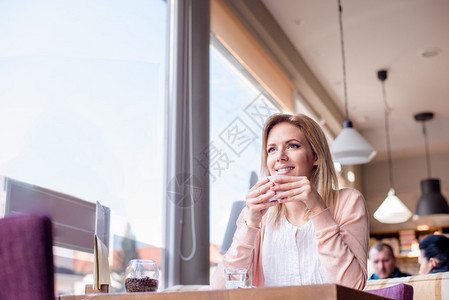 在咖啡馆喝咖啡包着咖啡和放松的年轻美图片