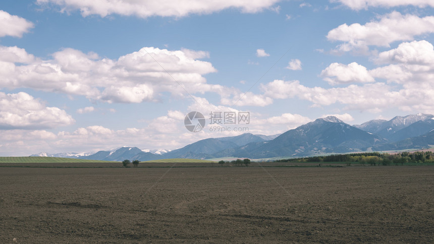 绿草和本底高山的草原上阴暗的暴风云图片