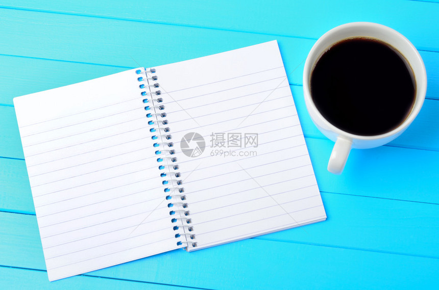 空记事本蓝色木桌上放着咖啡图片
