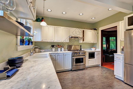 厨房内设计有白色柜子大理石柜顶不锈钢器和小木质楼层的明亮图片