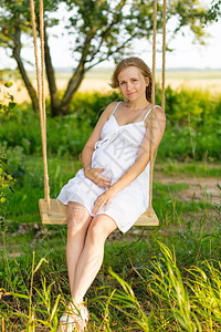 夏天坐在户外摇摆的孕妇肖像画图片
