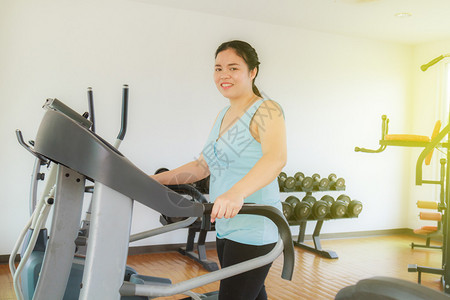 亚洲胖女人在健身房经营电动跑步机争图片
