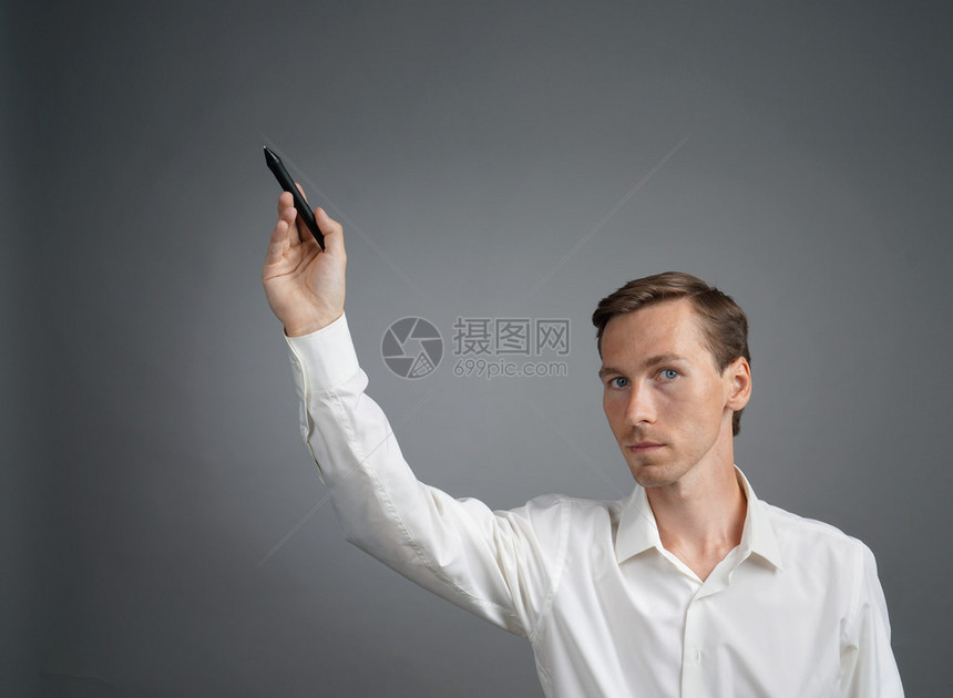 穿白衬衫的年轻人在玻璃板上写着有标记的东图片