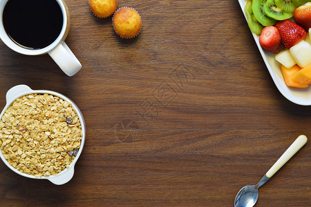一碗格兰诺拉麦片水果拼盘和木桌上的一杯咖啡健康的早餐健图片