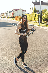 穿着时装的溜冰女孩在城市路上摆着板背景图片