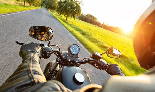 摩托车驾驶员在黄夕光照亮的高速公路上骑车图片