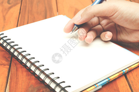 手握笔写在笔记本上图片