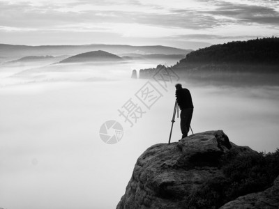 专业摄影师用三脚架在悬崖上工作高清图片