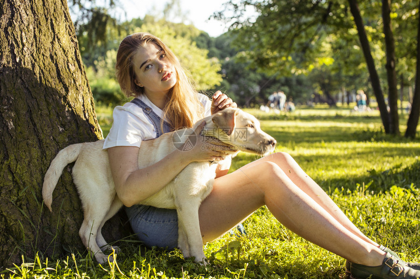 年轻有吸引力的金发美女在夏日绿公园玩她的狗生活方式的人概念图片