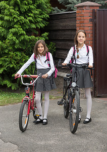 两个穿着校服带着自行车在街上行图片