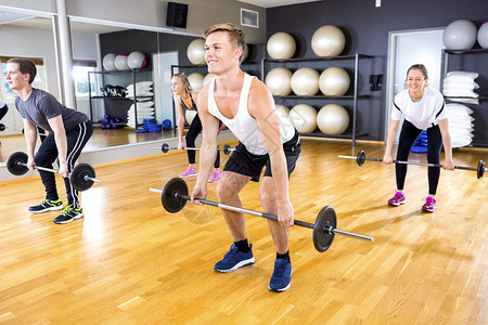 集中的健身组在健身房做有重量的起重物团图片
