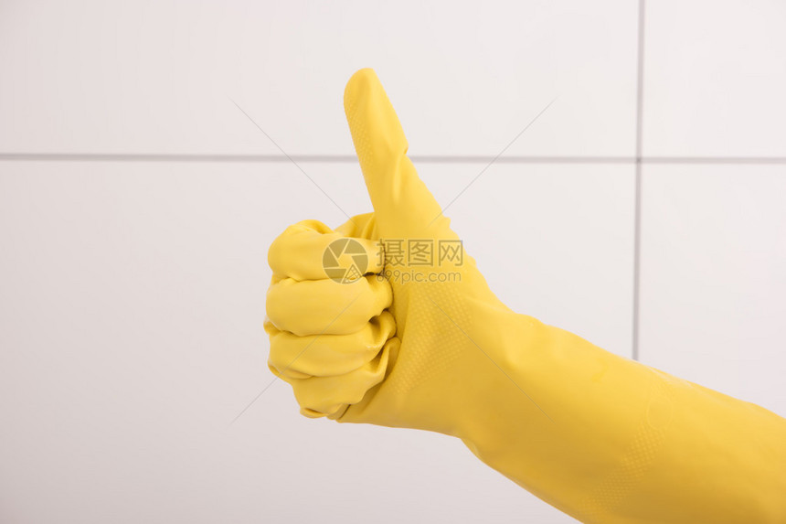 用黄色橡皮手套把拇指举起来清洁图片