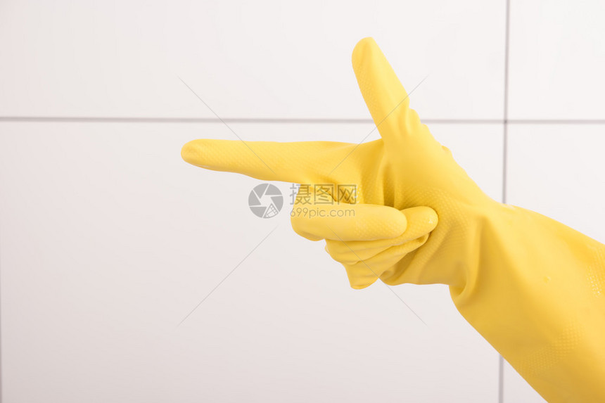 黄色橡胶手套中的女手显示有食指图片