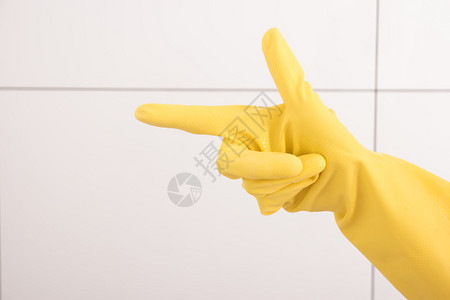 黄色橡胶手套中的女手显示有食指图片