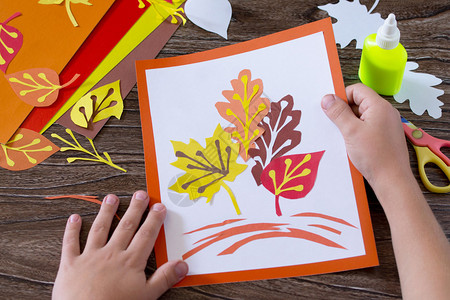 木制背景的彩色纸的秋叶儿童手工艺品页儿童艺图片