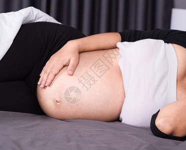 睡在家中卧室床上的孕妇肚子紧图片