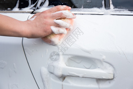 男子手洗车配有海绵和泡沫图片