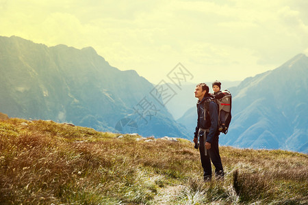 父亲带着孩子在背靠的山背上徒步旅行一家人在山上徒步旅行Mangart图片