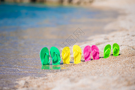 蓝色大海前沙滩上的家庭人字拖图片