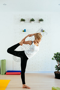 一个有吸引力的做瑜伽的年轻女子摆出平衡和伸展的姿势健康的概图片